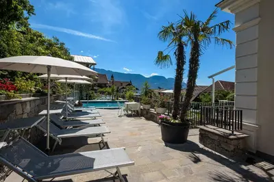 a row of lounge chairs and an umbrella next to a pool at Villa Maria in Tirolo