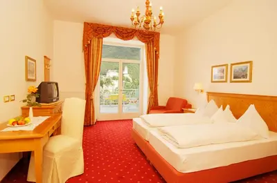 a bedroom with a bed and a desk and a television at Villa Maria in Tirolo