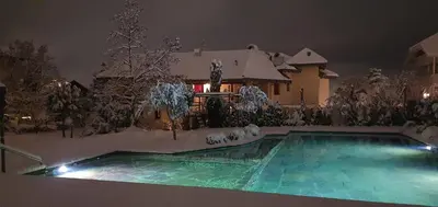 a house with a swimming pool in the snow at Bio Hotel Kaufmann in Ora/Auer