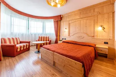 a bedroom with a bed and a chair and a table at Lady Maria Hotel Wellness & Resort in Fondo
