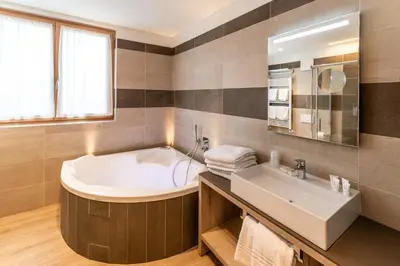 a bathroom with a tub and a sink at Lady Maria Hotel Wellness & Resort in Fondo