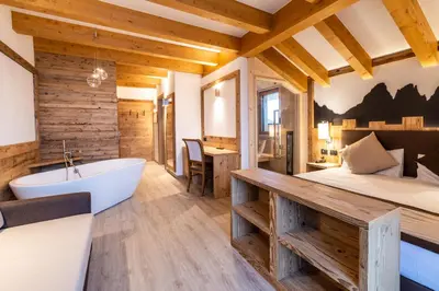 a bedroom with a tub and a bed and a bed and a desk at Lady Maria Hotel Wellness & Resort in Fondo