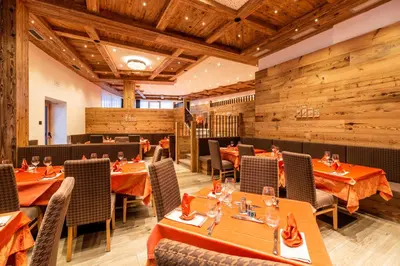 a restaurant with wooden walls and tables and chairs at Lady Maria Hotel Wellness & Resort in Fondo