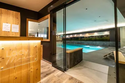 a room with a swimming pool and glass walls at Lady Maria Hotel Wellness & Resort in Fondo