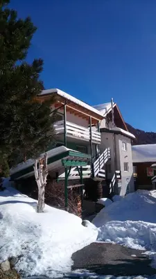 a house in the snow with a green porch at Alpen Ferienwohnung II in Lappago