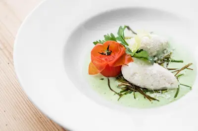 a plate of food with a red flower on it at Hotel Gran Ciasa in Colfosco