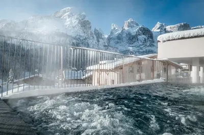 a hot tub with snow covered mountains in the background at Hotel Gran Ciasa in Colfosco