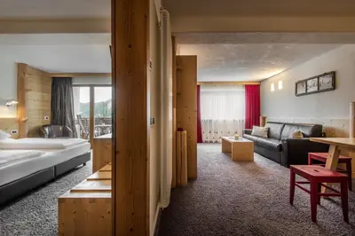 a hotel room with a bed and a living room at Hotel Gran Ciasa in Colfosco