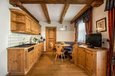 a kitchen with wooden cabinets and a table at Residence Vila in Colfosco