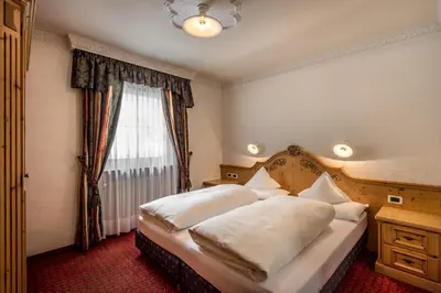 a bedroom with a bed with white pillows and a window at Residence Vila in Colfosco