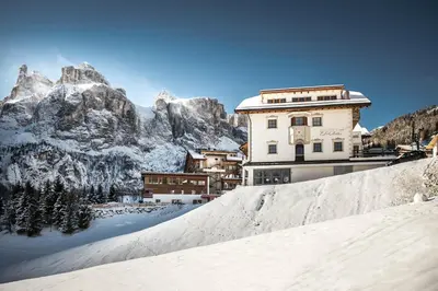a building in the snow in front of a mountain at Residence Vila in Colfosco