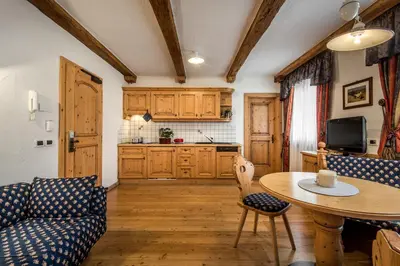 a living room with a table and a couch and a kitchen at Residence Vila in Colfosco