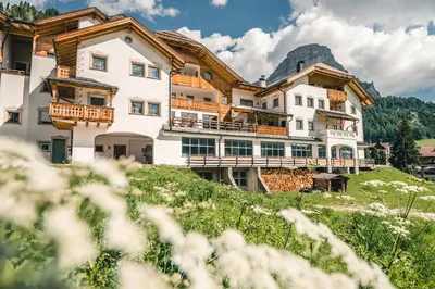 a large building on a hill with a mountain at Residence Vila in Colfosco