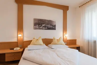 a bedroom with a large white bed with two pillows at Pension Weingarten in Lana