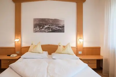 a bedroom with a bed with white sheets and pillows at Pension Weingarten in Lana