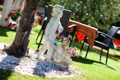 a statue of a boy walking next to a tree at Pension Weingarten in Lana