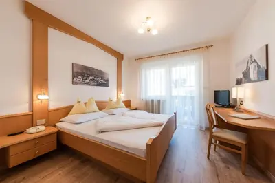 a bedroom with a bed and a desk and a computer at Pension Weingarten in Lana