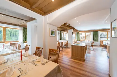 a dining room with tables and chairs and windows at La Stua in San Cassiano