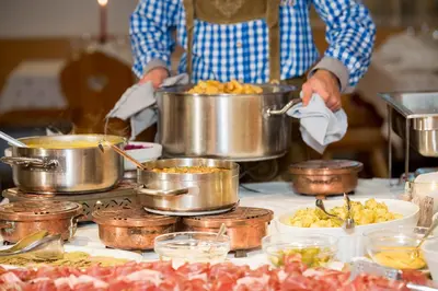 a person preparing food in pots on a table at La Stua in San Cassiano