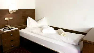 a bedroom with a bed with white pillows and a phone at Hotel Weisses Lamm in Monguelfo