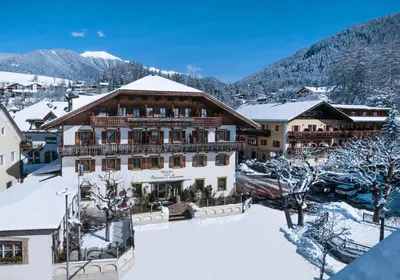 a large building with snow on the ground at Hotel Weisses Lamm in Monguelfo