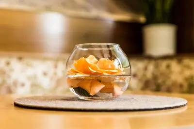 a glass vase filled with fruit in water on a table at Hotel Weisses Lamm in Monguelfo