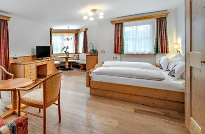 a bedroom with a large bed and a desk at Alpenhotel Plaza in Santa Cristina in Val Gardena