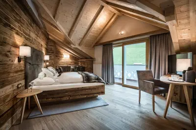 a bedroom with a large white bed and a desk at Alpenhotel Plaza in Santa Cristina in Val Gardena