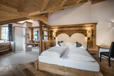 a bedroom with a large bed with a wooden headboard at Alpenhotel Plaza in Santa Cristina in Val Gardena