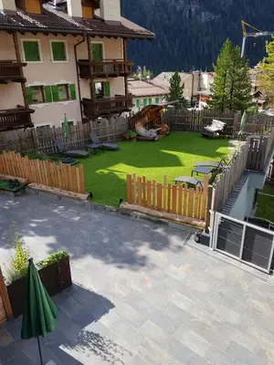 a backyard with a fence and a yard with a playground at Klimahouse North in Campitello di Fassa
