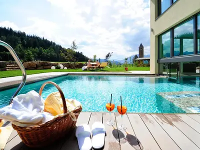 a picnic table next to a swimming pool with two glasses at Hotel Sulfner in Avelengo