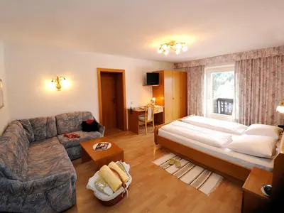 a bedroom with a large bed and a couch at Hotel Sulfner in Avelengo