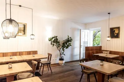 a restaurant with wooden tables and chairs and a plant at Garni Hotel Tauber in Bressanone