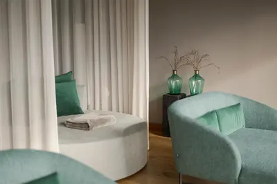 a living room with a chair and a chair with a pillow at La Maiena Meran Resort in Marlengo