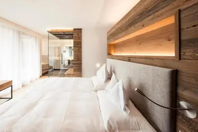 a bedroom with a bed with a wooden wall at Hotel Petrus in Brunico