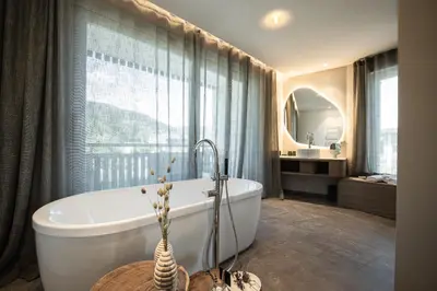 a bathroom with a tub and a large window at Hotel Petrus in Brunico