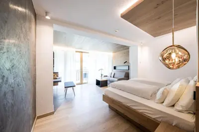 a bedroom with a large bed and a living room at Hotel Petrus in Brunico