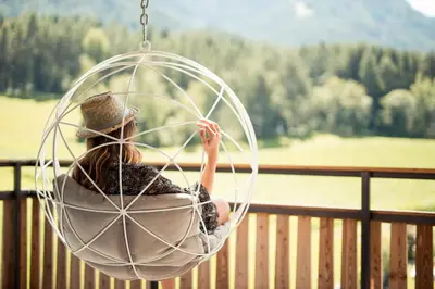 a woman sitting in a ball swing on a porch at Hotel Petrus in Brunico