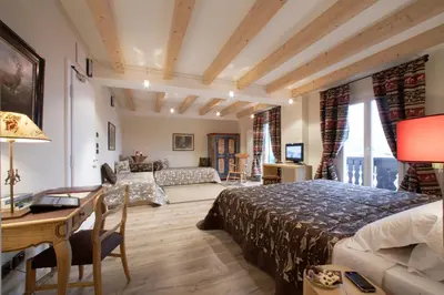 a bedroom with a bed and a desk and a couch at Hotel Savoia dal 1924 in San Martino di Castrozza