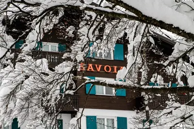 a snow covered building with a sign that reads await at Hotel Savoia dal 1924 in San Martino di Castrozza