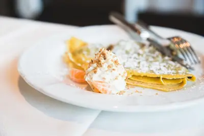 a plate of pancakes with powdered sugar and a fork at Hotel Savoia dal 1924 in San Martino di Castrozza