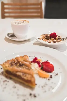 a table with two plates of food and a cup of coffee at Hotel Savoia dal 1924 in San Martino di Castrozza