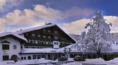 a large building with a snow covered christmas tree at Hotel Savoia dal 1924 in San Martino di Castrozza