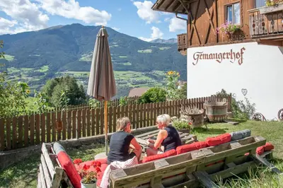 two women sitting on a couch in front of a building at Gemangerhof in Bressanone