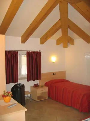 a bedroom with a red bed in a room with wooden ceilings at Hotel Victory in Taio