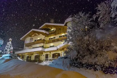 a building with a patio with tables and chairs at Pineta Pastry Hotel in Rocca Pietore