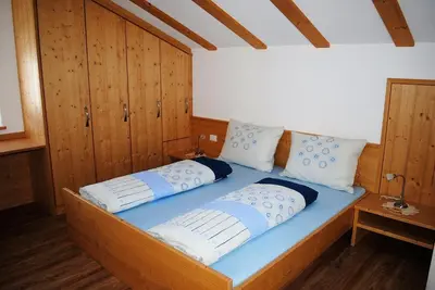 a bed in a room with wooden walls and wooden floors at Finggeneislerhof in Villandro