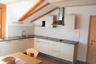 a kitchen with white cabinets and a wooden table at Finggeneislerhof in Villandro