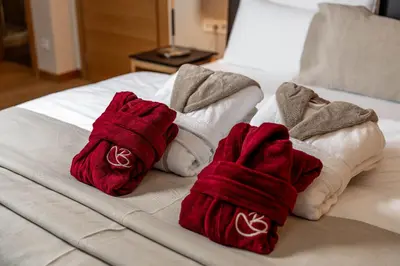 two red and white towels on a bed at Biancaneve Family Hotel in Selva di Val Gardena