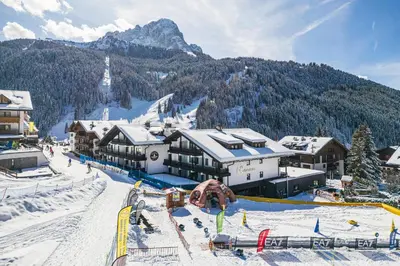a ski lodge in the mountains with snow on the ground at Biancaneve Family Hotel in Selva di Val Gardena